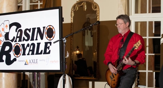 A man playing a guitar in front of a sign that says casino royale.