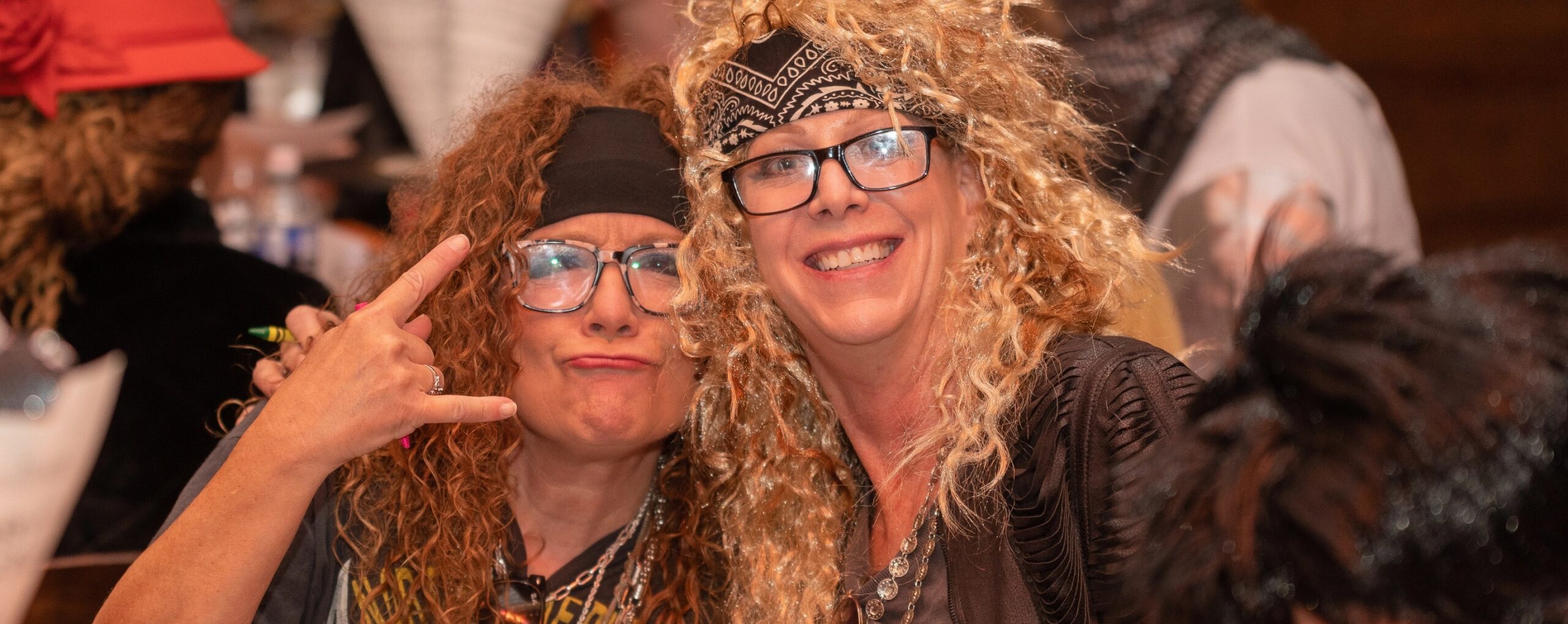 Two women with wigs and glasses posing for a photo.