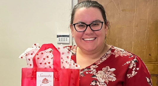 A woman with glasses holding a gift bag.